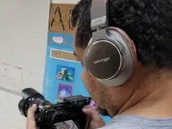 Professor de fones filmando com câmera durante a oficina de audiovisual